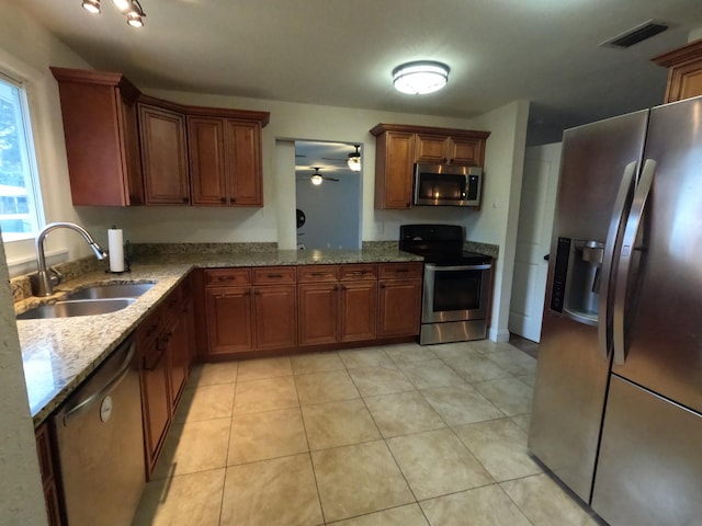 kitchen with ceiling fan, light tile patterned floors, sink, stainless steel appliances, and light stone countertops