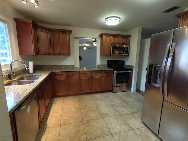kitchen with a sink, light stone countertops, stainless steel appliances, and visible vents