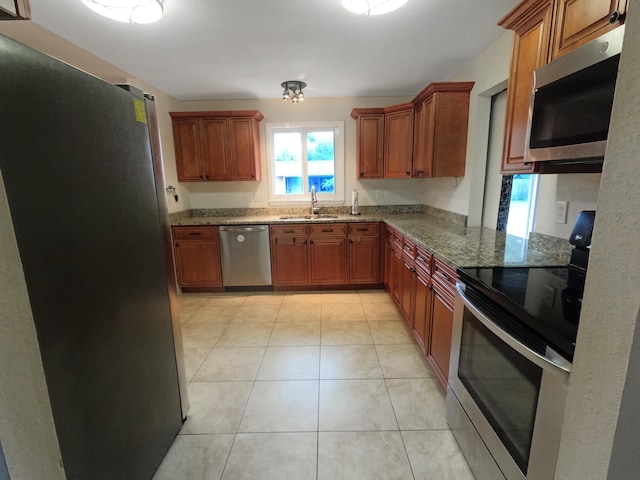 kitchen with appliances with stainless steel finishes, stone countertops, sink, and light tile patterned floors