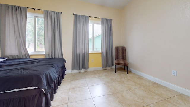 bedroom with light tile patterned floors and baseboards
