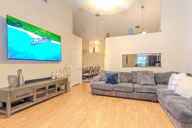 living room featuring a towering ceiling, hardwood / wood-style floors, and ceiling fan