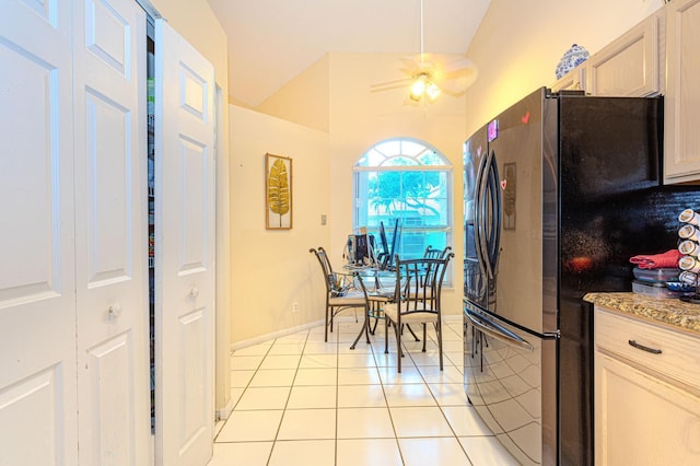 kitchen with ceiling fan, light tile patterned floors, stainless steel refrigerator, light brown cabinetry, and vaulted ceiling