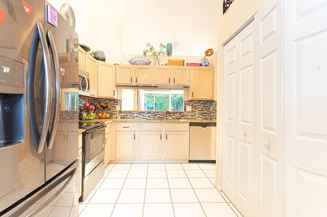 kitchen with light brown cabinetry, stainless steel appliances, light tile patterned floors, and decorative backsplash