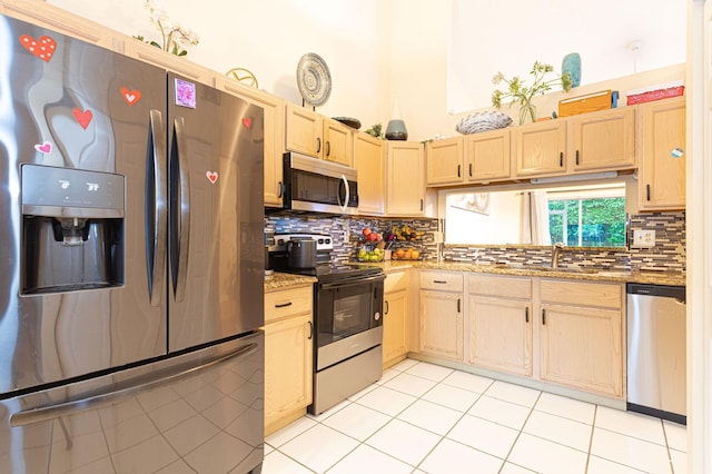 kitchen featuring tasteful backsplash, light brown cabinets, light stone countertops, stainless steel appliances, and sink