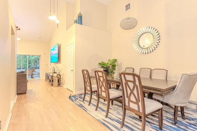 dining room featuring light hardwood / wood-style flooring and high vaulted ceiling