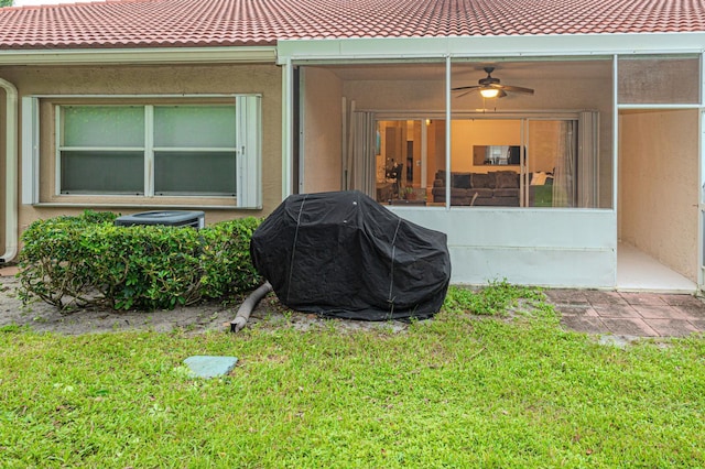 view of exterior entry featuring ceiling fan and a lawn