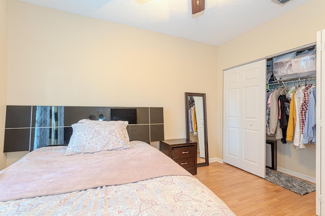 bedroom with ceiling fan, a textured ceiling, a closet, and light hardwood / wood-style floors