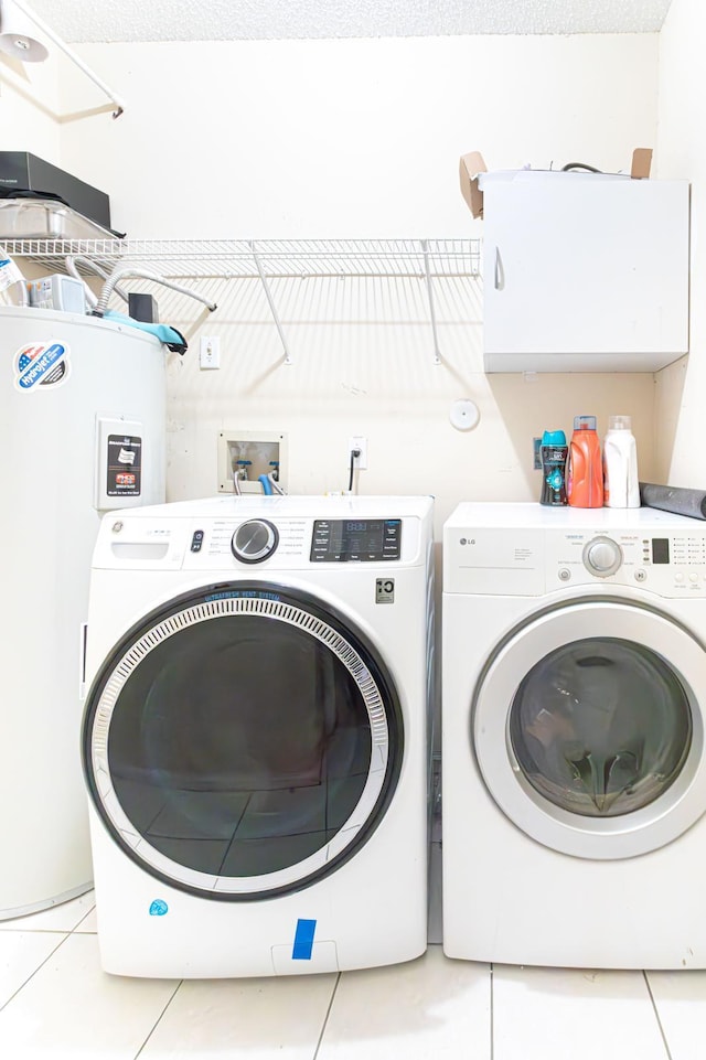 washroom with washer and clothes dryer, light tile patterned flooring, and electric water heater