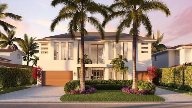 view of front facade with decorative driveway, an attached garage, and stucco siding