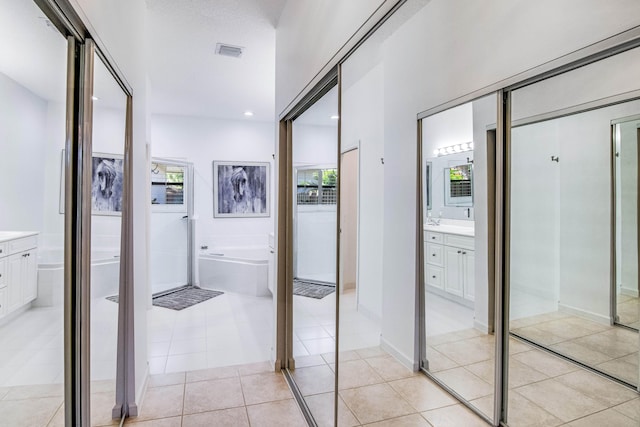 corridor featuring a textured ceiling, a healthy amount of sunlight, and light tile patterned floors