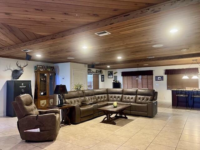 living room featuring beam ceiling, light tile patterned floors, and wood ceiling