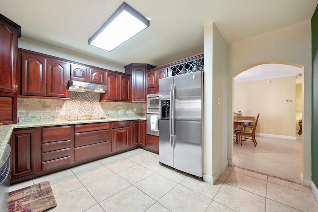 kitchen with backsplash, light stone counters, light tile patterned flooring, and appliances with stainless steel finishes