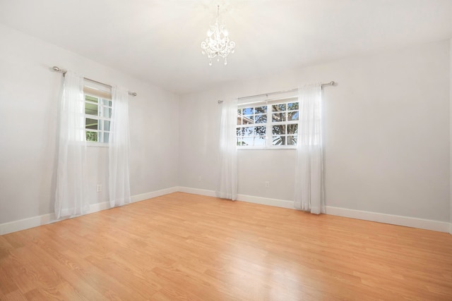 unfurnished room with light hardwood / wood-style floors and a notable chandelier