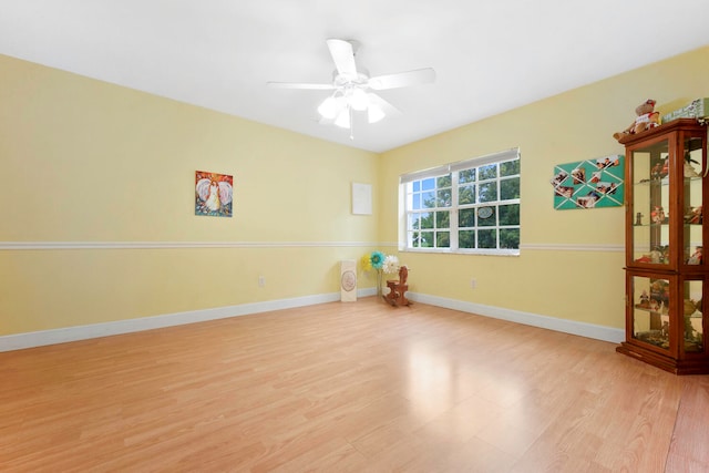 empty room with ceiling fan and light hardwood / wood-style flooring