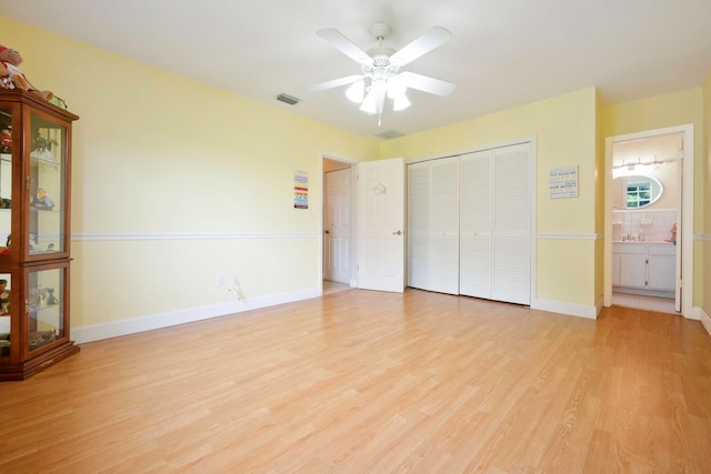 unfurnished bedroom featuring ceiling fan, a closet, connected bathroom, and light hardwood / wood-style flooring