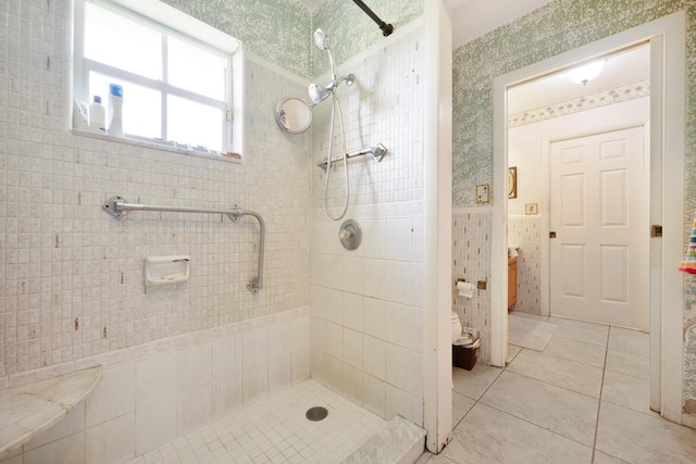 bathroom featuring tile patterned floors, toilet, tiled shower, and tile walls