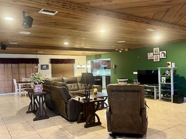 living room with beam ceiling, light tile patterned floors, and wooden ceiling