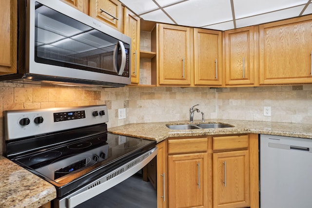 kitchen featuring light stone counters, tasteful backsplash, sink, and stainless steel appliances