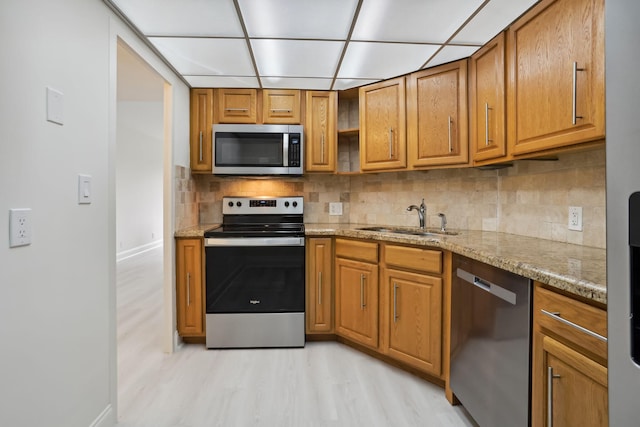 kitchen with light hardwood / wood-style floors, stainless steel appliances, light stone countertops, tasteful backsplash, and sink