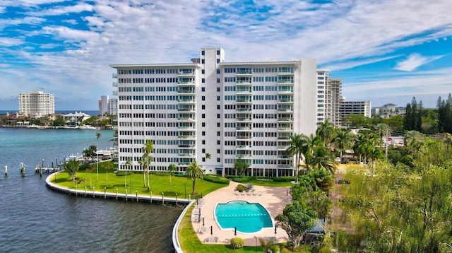 view of building exterior featuring a community pool and a water view