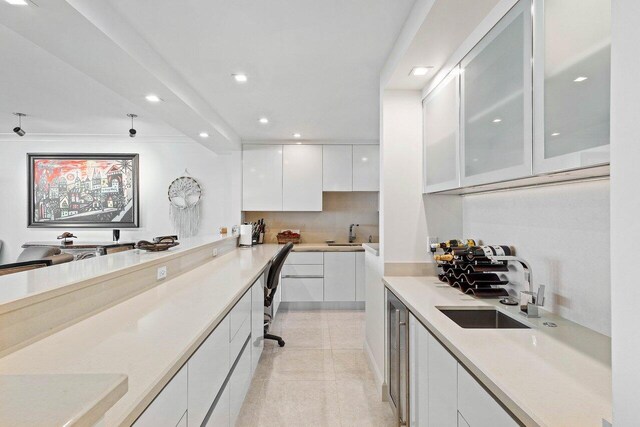 kitchen featuring sink, white cabinetry, tasteful backsplash, and light tile flooring