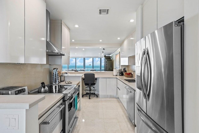 kitchen with light tile floors, appliances with stainless steel finishes, white cabinetry, and kitchen peninsula