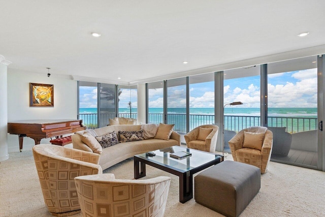 carpeted living room with a water view and a wall of windows