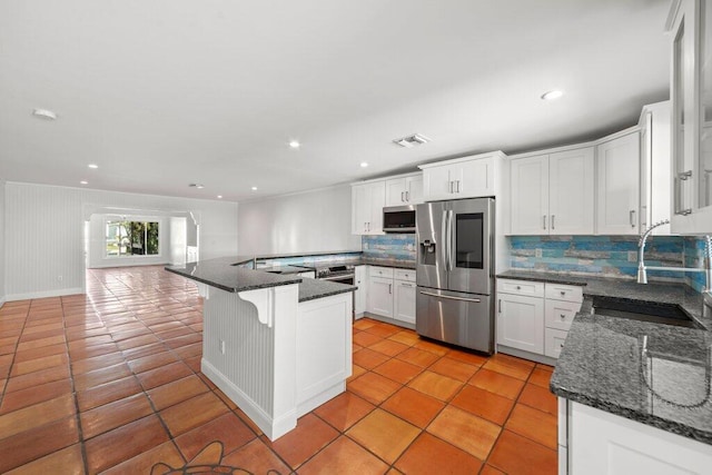 kitchen with tasteful backsplash, appliances with stainless steel finishes, sink, and white cabinets