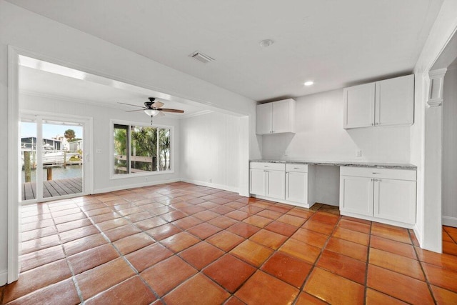 kitchen featuring a water view, light tile patterned floors, ornamental molding, ceiling fan, and white cabinets