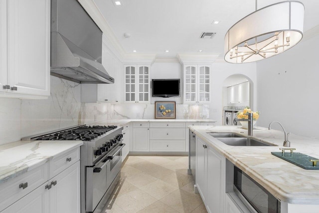 kitchen with backsplash, stainless steel appliances, wall chimney exhaust hood, white cabinetry, and sink