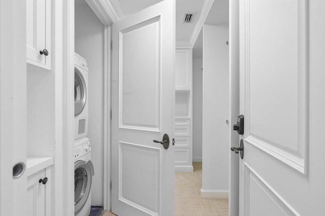 washroom featuring light colored carpet, stacked washer / drying machine, and ornamental molding