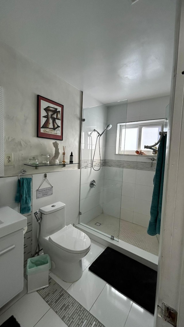 bathroom with tile patterned flooring, vanity, toilet, and a tile shower