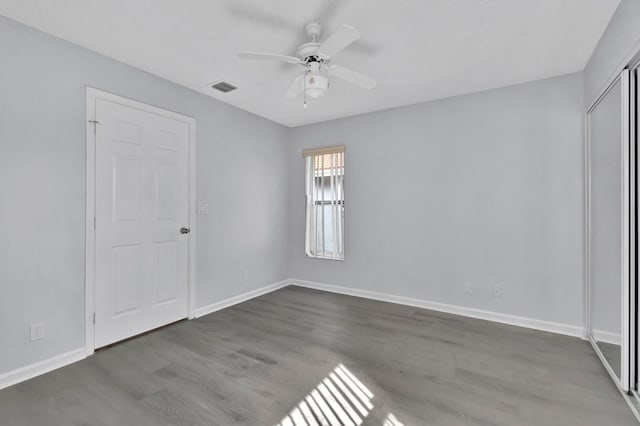 unfurnished room with ceiling fan and dark wood-type flooring