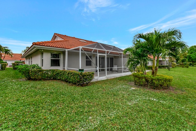 rear view of house featuring a yard, a patio area, and a lanai