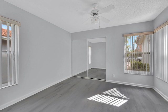 empty room with ceiling fan, dark wood-type flooring, and a textured ceiling