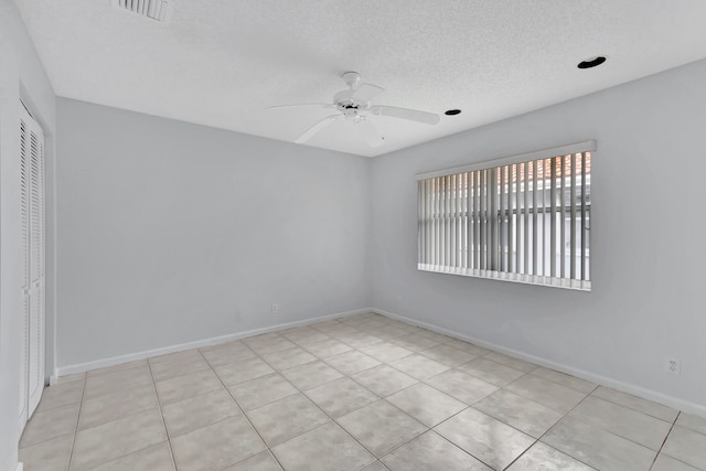 tiled empty room featuring a textured ceiling and ceiling fan