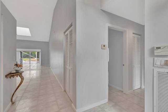 hall with light tile floors and vaulted ceiling with skylight