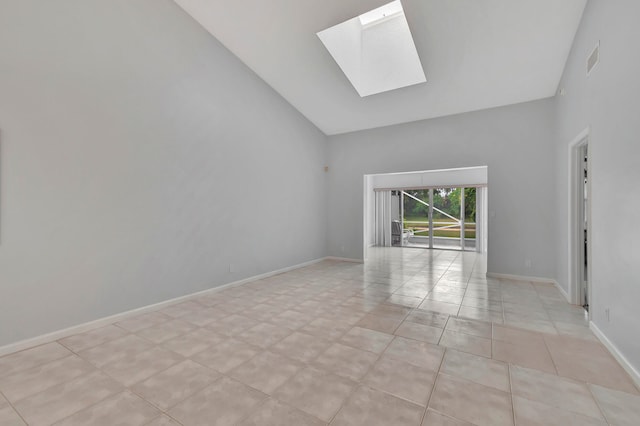 tiled empty room with high vaulted ceiling and a skylight