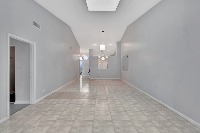 tiled foyer entrance featuring vaulted ceiling with skylight and a chandelier