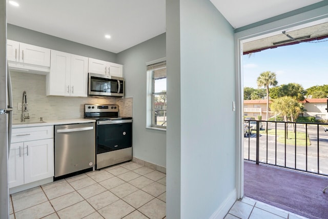 kitchen featuring appliances with stainless steel finishes, white cabinets, sink, backsplash, and light colored carpet