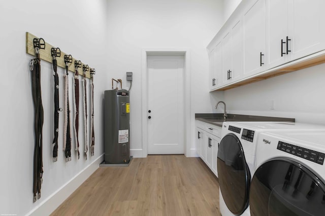 washroom featuring cabinets, washing machine and clothes dryer, light hardwood / wood-style flooring, water heater, and sink