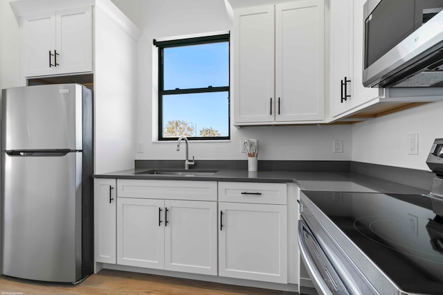 kitchen with light hardwood / wood-style floors, white cabinets, stainless steel appliances, and sink