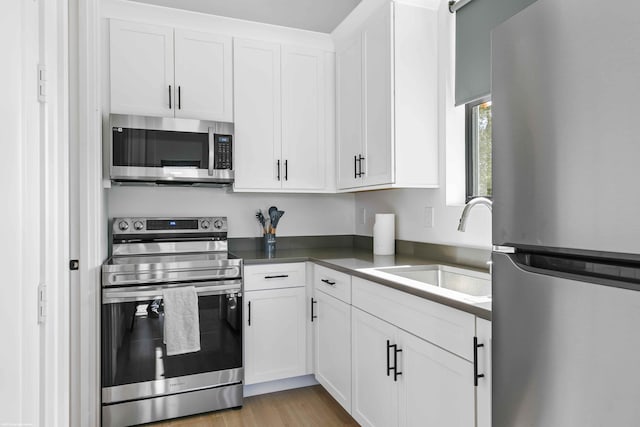 kitchen featuring stainless steel appliances, sink, light wood-type flooring, and white cabinets