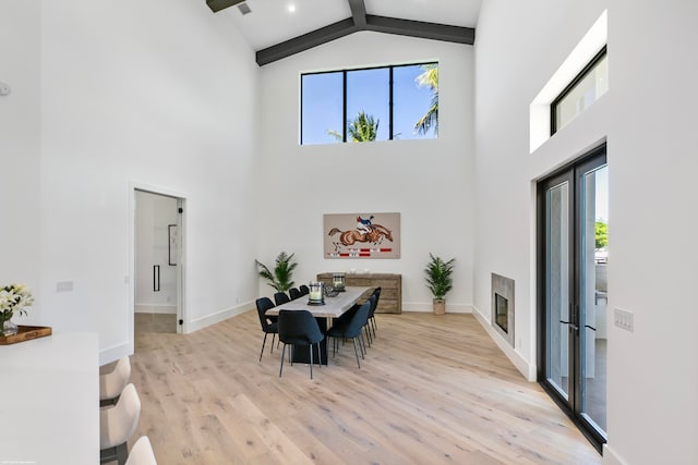 dining area featuring light wood-type flooring, high vaulted ceiling, beamed ceiling, and plenty of natural light