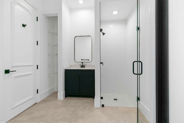 bathroom with a shower with door, vanity, and tile patterned flooring