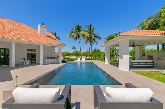 view of pool with a patio, ceiling fan, a bar, and an outdoor hangout area