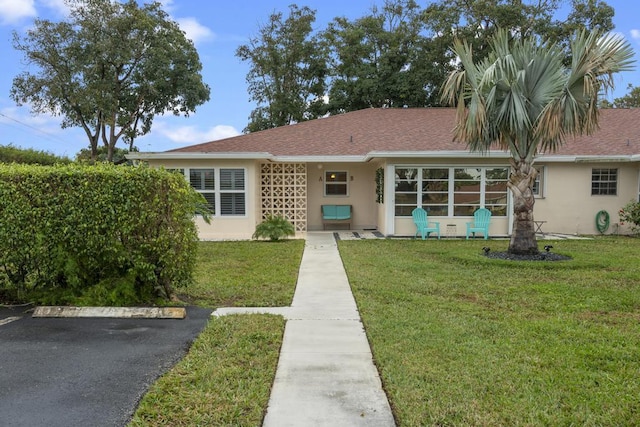 view of front of home featuring roof with shingles, a front lawn, and stucco siding