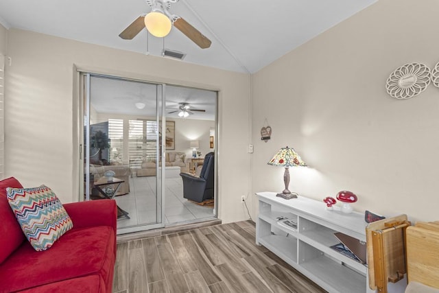 living area featuring vaulted ceiling, wood finished floors, and a ceiling fan