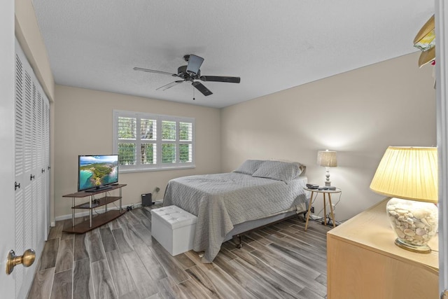 bedroom featuring ceiling fan, a closet, baseboards, and wood finished floors