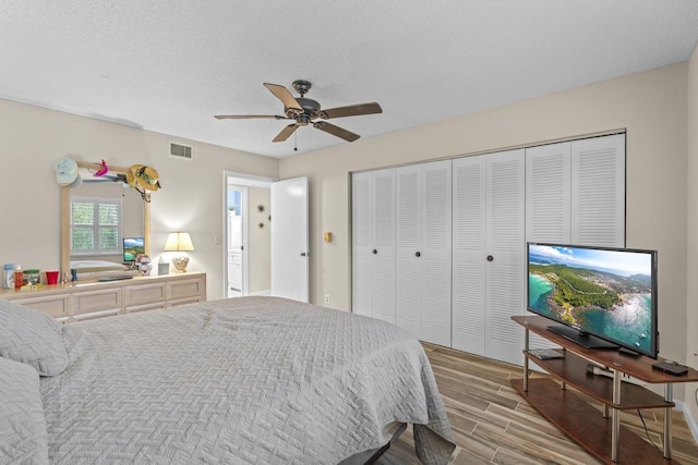 bedroom with a ceiling fan, wood finish floors, a closet, and visible vents